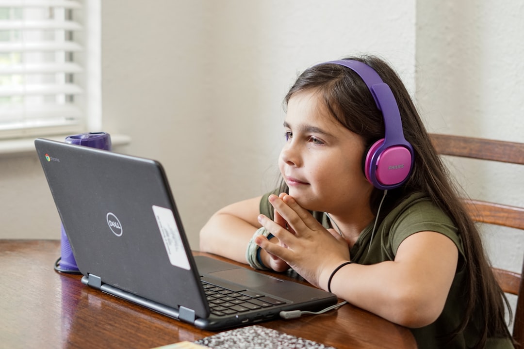 Oferta Young cute elementary aged girl with headphones on looking at a laptop while participating and learning in a remote virtual learning class during the COVID-19 pandemic quarantine.