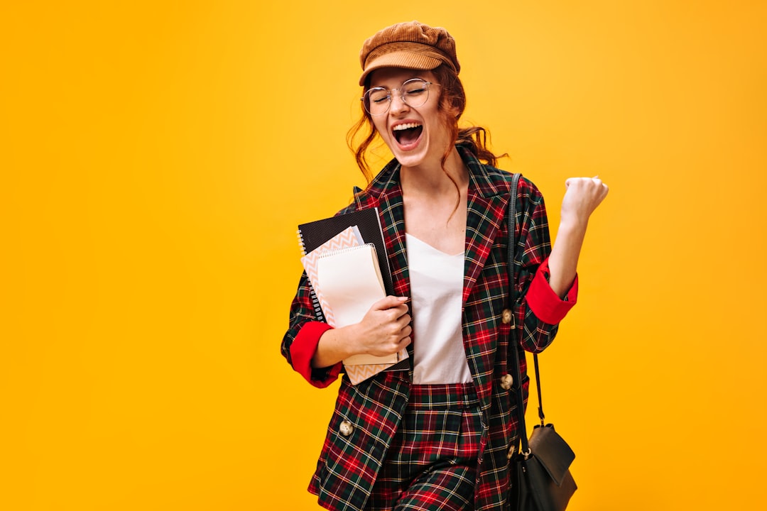 Oferta a-woman-in-a-plaid-jacket-holding-a-book-and-a-bag-b3zvfcibzja